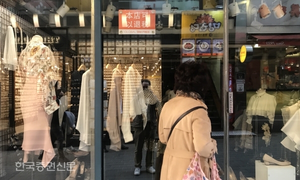 25일 대한민국의 중심, 서울의 번화가인 명동도 코로나 여파로 멈춰섰다. 관광객들이 줄면서 거리는 한산하다. 문 닫은 가게와 휴업 중인 가게들로 활기를 찾아볼 수 없다. 사진은 한 여성이 문 닫힌 상점 앞에서 진열된 옷을 구경하고 있다.